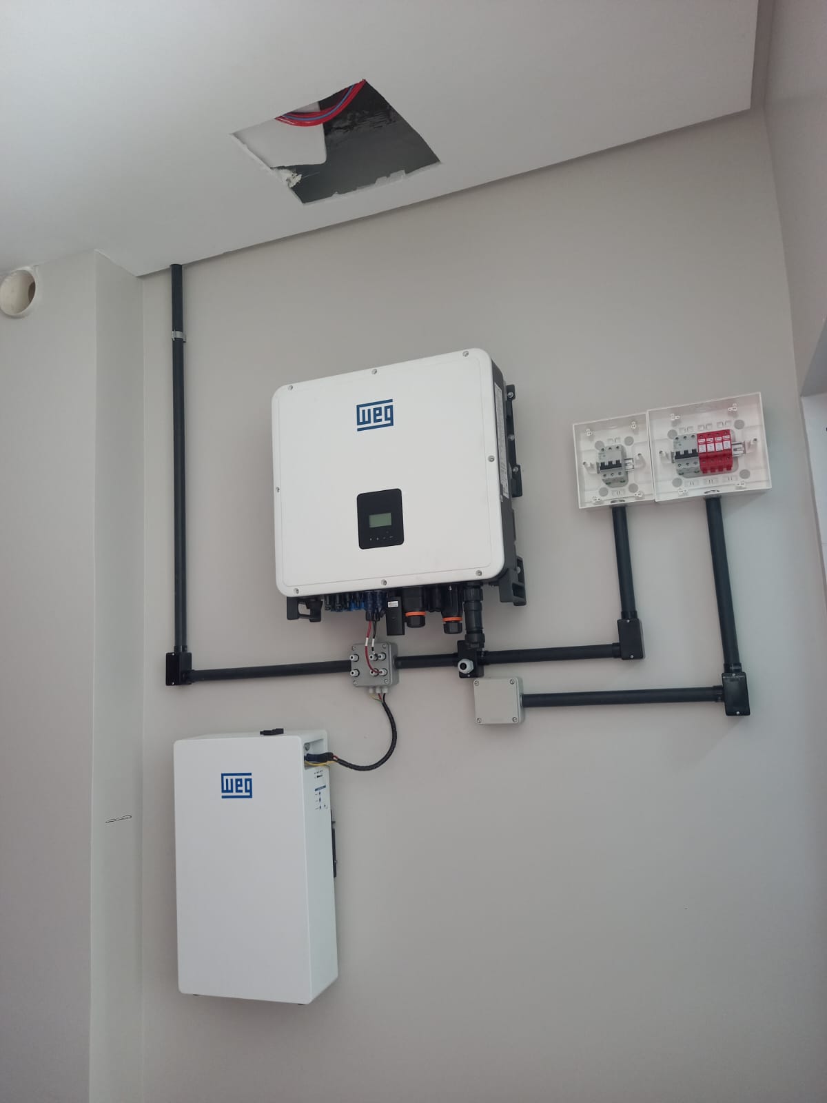 Inversor e bateria WEG instalados com quadro de proteção e eletrodutos organizados