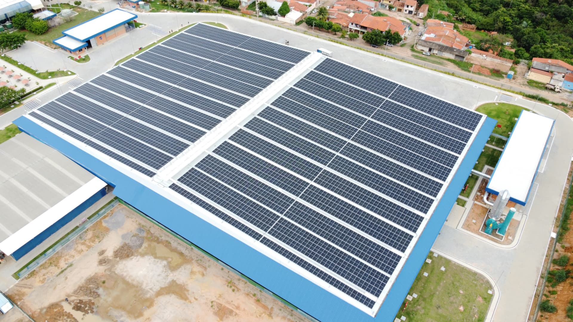 Vista aérea de uma grande cobertura industrial preenchida por módulos fotovoltaicos