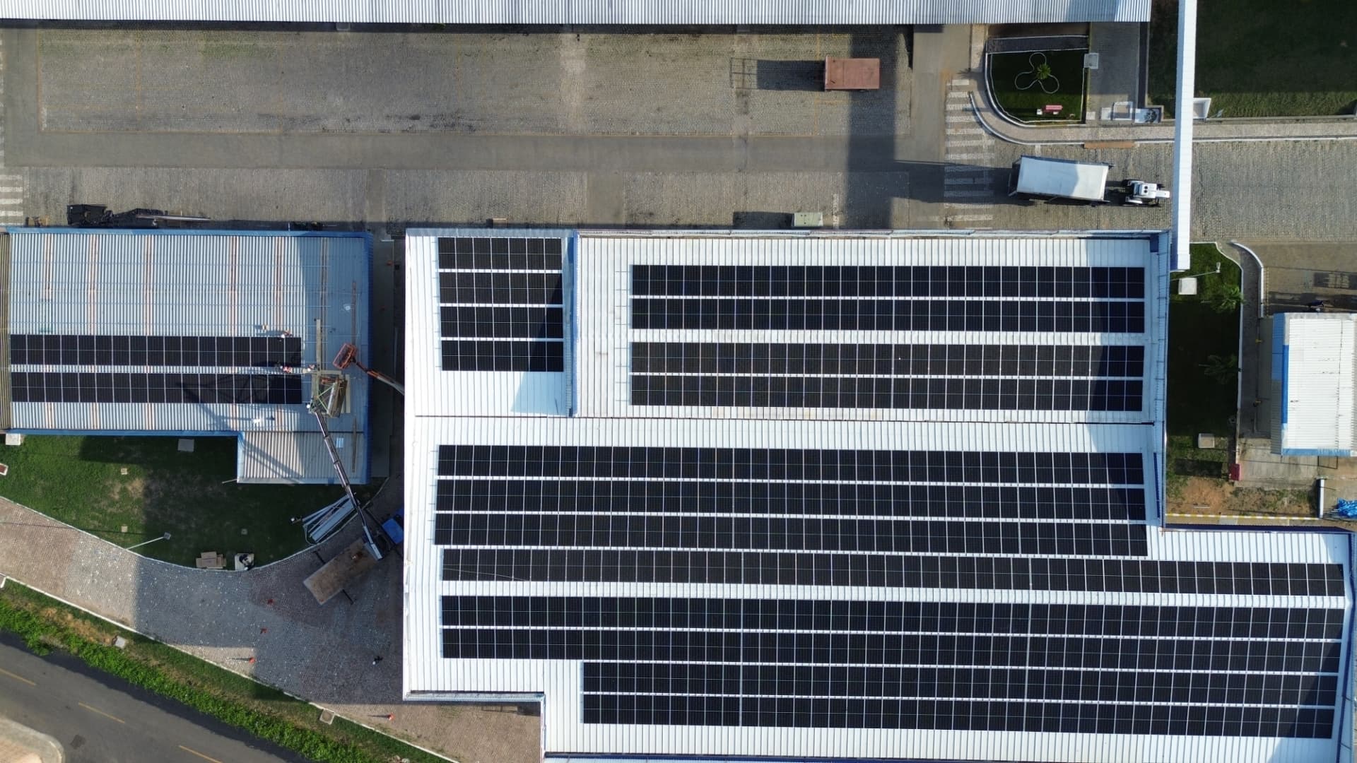 Vista vertical de cobertura comercial com grandes conjuntos de módulos fotovoltaicos