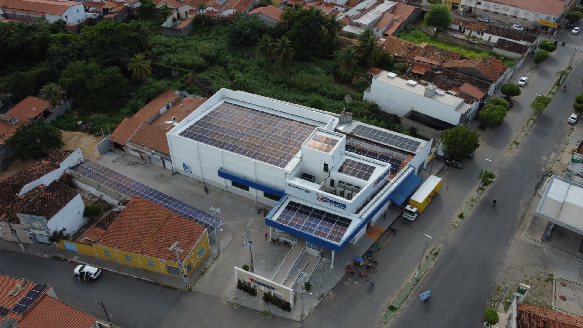 Vista aérea de comércio com módulos fotovoltaicos distribuídos por telhados e coberturas